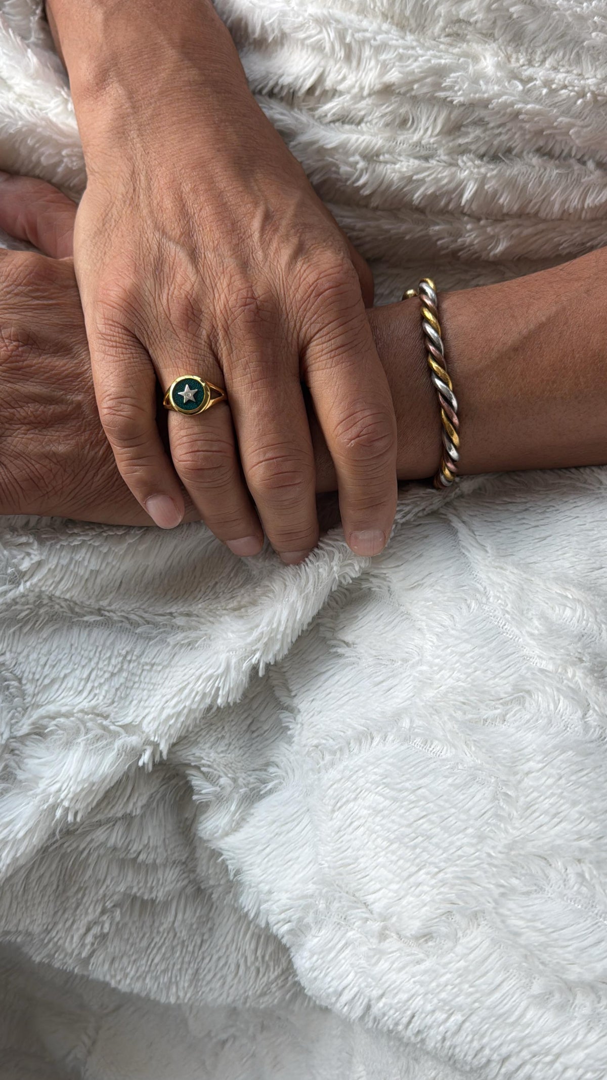Two hands holding each other on a white textured surface