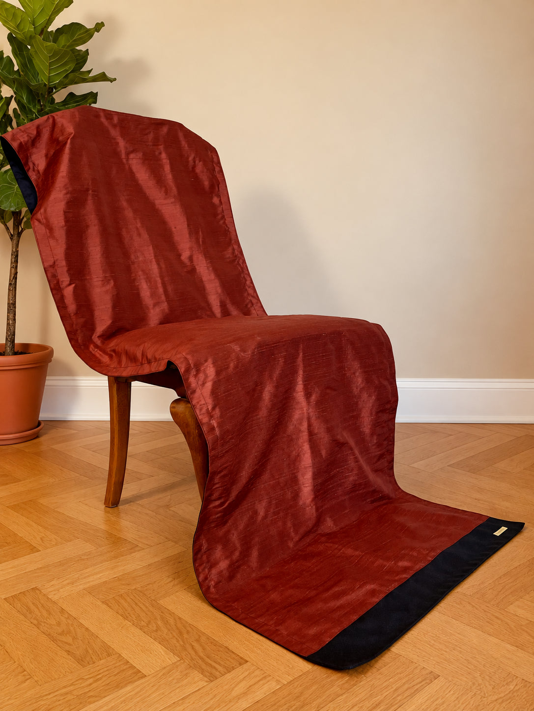 Copper red Dhyanam silk and wool blanket draped over a chair and beneath the feet; blanket component of the Chair Meditation Set