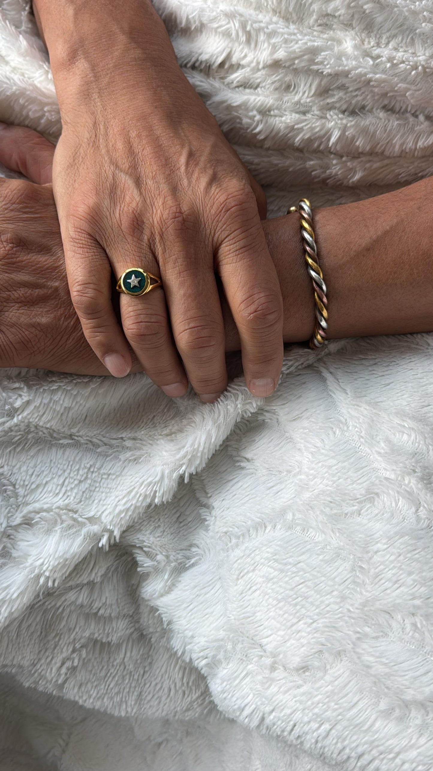 Two hands holding each other on a white textured surface