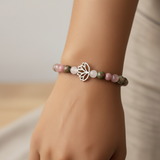 Beaded bracelet with a silver lotus flower charm on a wooden surface